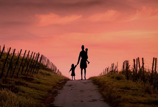 Una madre y sus dos hijos se alejan caminando por el campo sin rumbo